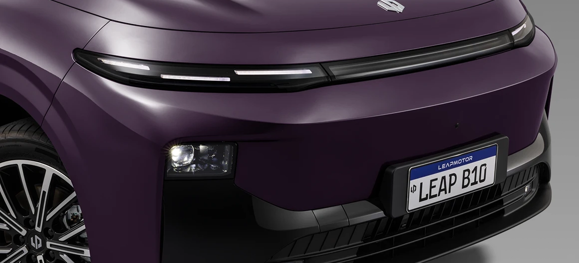 Detalhe frontal do Leapmotor B10 Detalhe da parte frontal do Leapmotor B10 roxo metálico, com farol em LED fino, capô liso e placa com o texto “LEAP B10”.